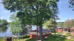 A view of three of the cabins at Twin Bay Resort on the lake showing trees, picnic tables, cabins, and the lake.