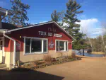 Outside view of the front of twin bay resort in the summer. Showing a red building with white lettering saying twin bay resort.