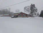 Outside view of twin bay resort in the winter. Showing a red building with white lettering saying twin bay resort. Everything is covered in snow.