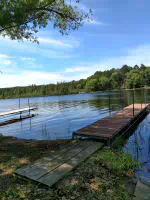 Outdoor picture during summertime showing Lake Nokomis, the shores of Lake Nokomis and two peirs in the lake.